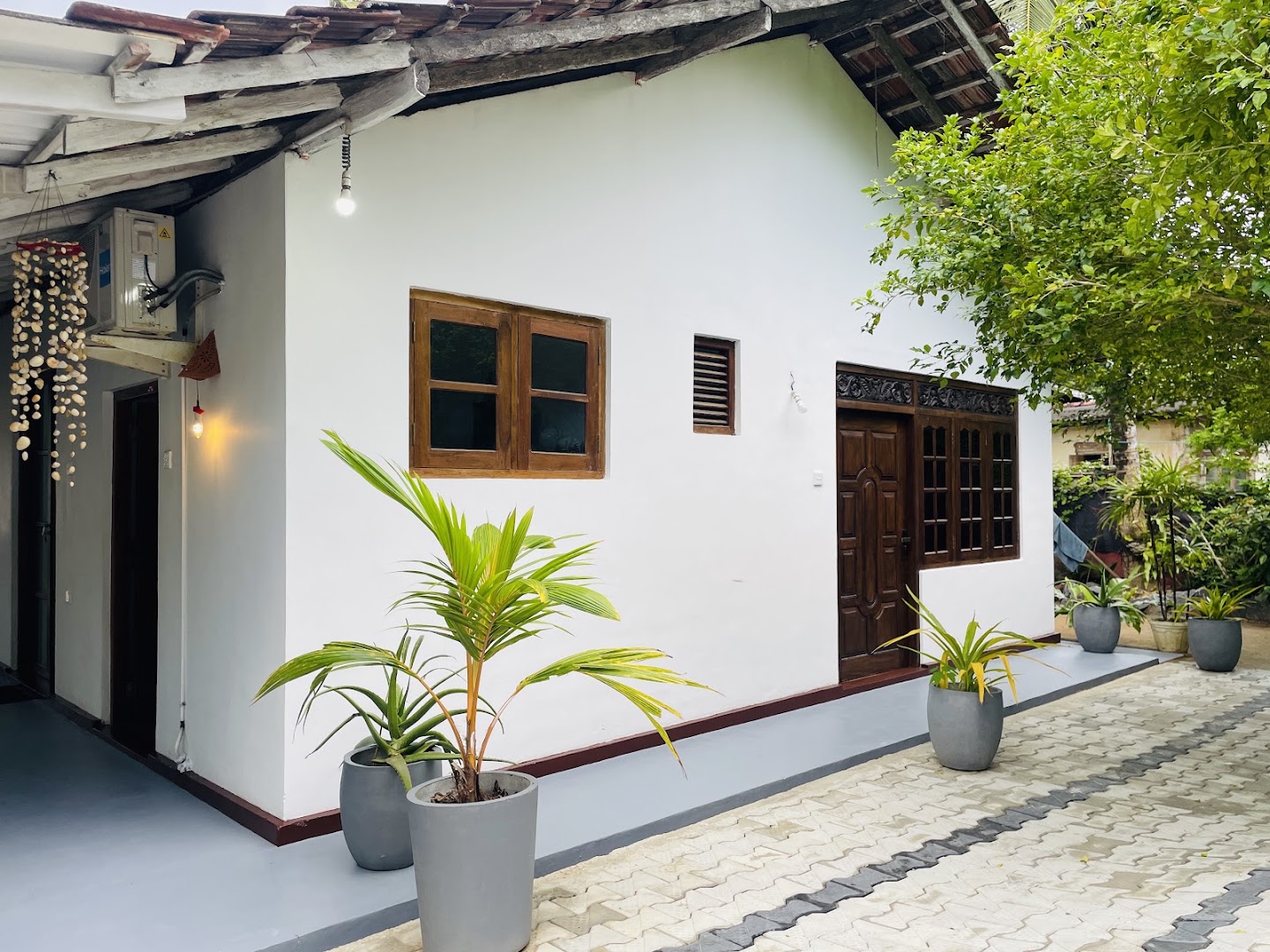 White villa walls, timber windows, potted palms, and a leafy courtyard at Lavo Villa