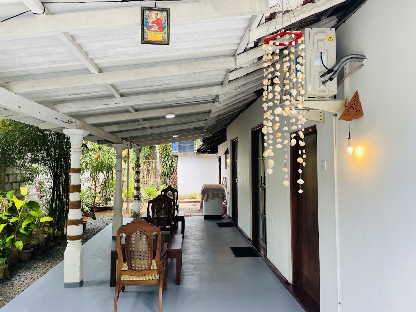 Shaded veranda with timber chairs, shell strings, and garden plants